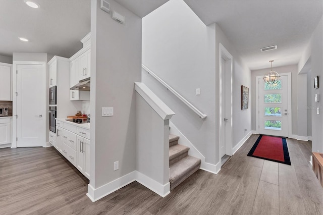 entrance foyer featuring visible vents, baseboards, wood finished floors, and stairway