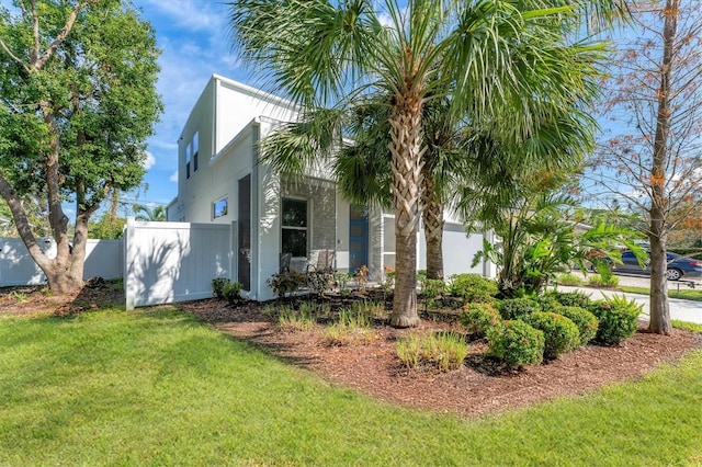 view of property exterior with a lawn, fence, and stucco siding