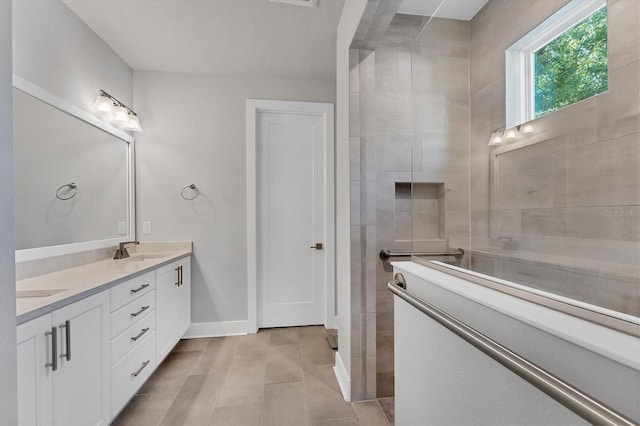 full bath featuring a sink, baseboards, walk in shower, and double vanity