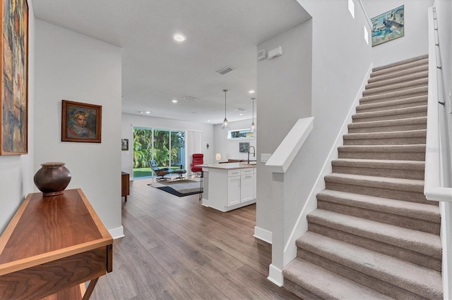 interior space with visible vents, wood finished floors, recessed lighting, baseboards, and stairs