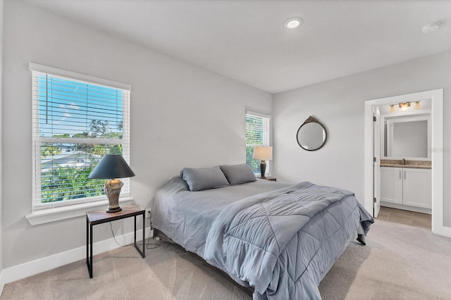 bedroom with light colored carpet and connected bathroom