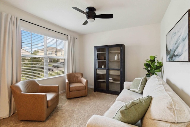 living area with light carpet and ceiling fan