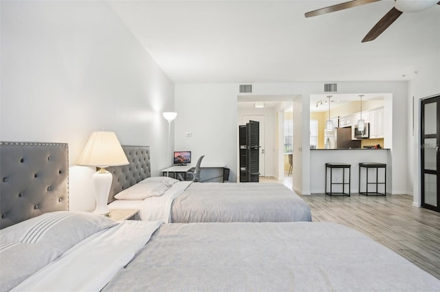 bedroom with stainless steel refrigerator, light wood-type flooring, and ceiling fan