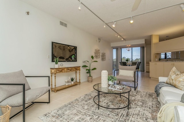 tiled living room featuring rail lighting, a textured ceiling, and ceiling fan