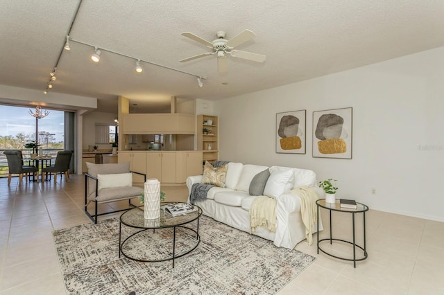 living room featuring track lighting, a textured ceiling, ceiling fan with notable chandelier, and light tile patterned floors