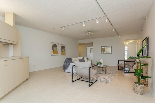 living room with a textured ceiling, rail lighting, light tile patterned floors, and ceiling fan