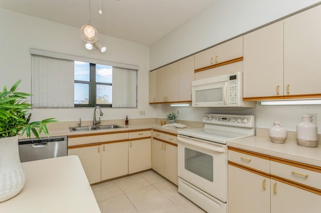 kitchen featuring cream cabinets, hanging light fixtures, sink, light tile patterned floors, and white appliances