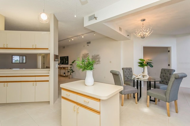 kitchen featuring light tile patterned flooring, hanging light fixtures, a textured ceiling, and kitchen peninsula