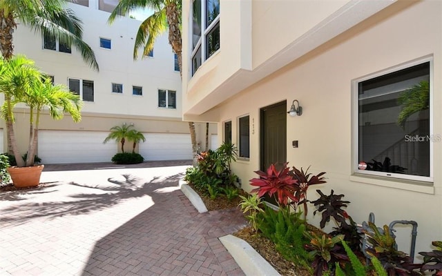 view of home's exterior featuring stucco siding, an attached garage, and decorative driveway