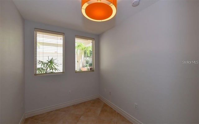 spare room featuring baseboards and light tile patterned flooring