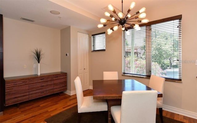 dining room with baseboards, an inviting chandelier, wood finished floors, and visible vents