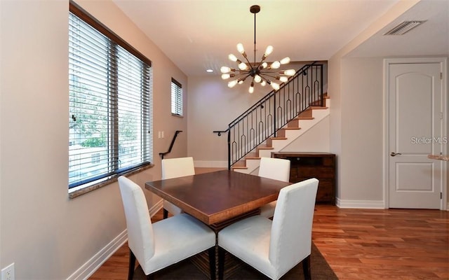 dining area featuring an inviting chandelier, stairs, baseboards, wood finished floors, and visible vents