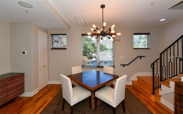 dining space featuring baseboards, stairs, wood finished floors, and a notable chandelier
