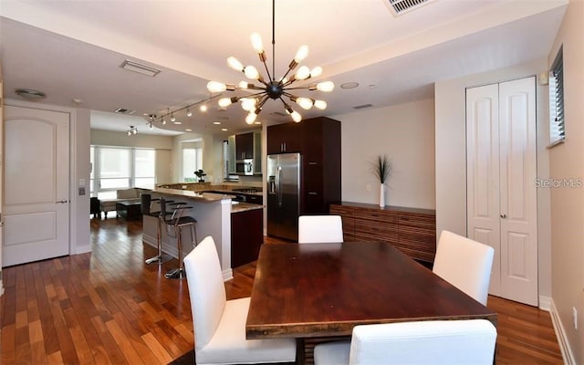 dining space with dark wood-style flooring, an inviting chandelier, and visible vents