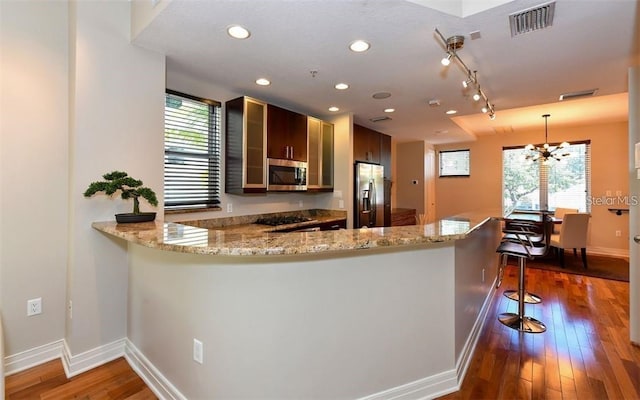 kitchen with a kitchen bar, visible vents, baseboards, a peninsula, and stainless steel appliances