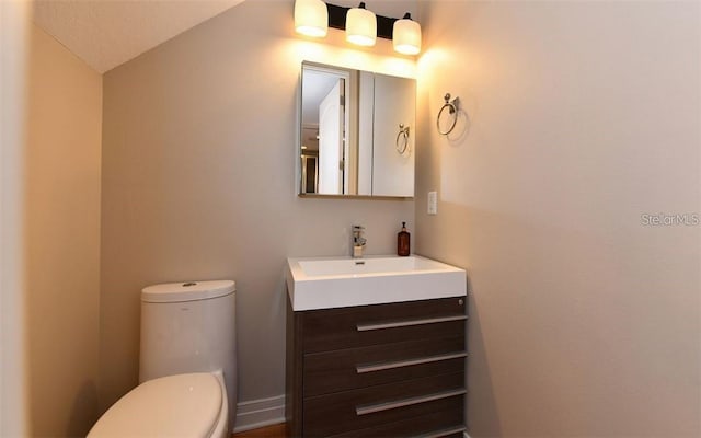 half bath featuring toilet, vaulted ceiling, and vanity