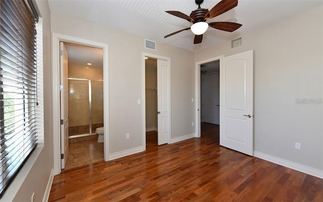 unfurnished bedroom with a spacious closet, ceiling fan, connected bathroom, and dark hardwood / wood-style flooring