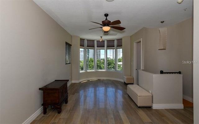 empty room with baseboards, ceiling fan, and wood finished floors
