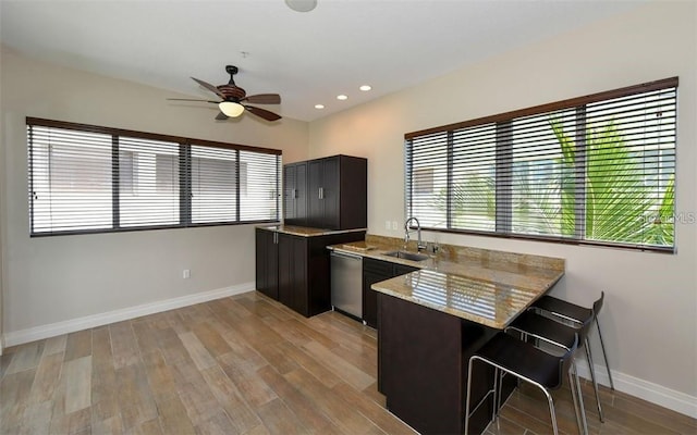kitchen with a sink, a peninsula, baseboards, a ceiling fan, and dishwasher