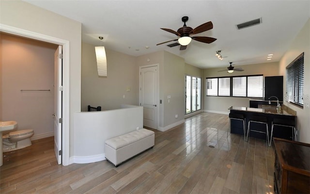 kitchen featuring visible vents, a ceiling fan, light wood-style floors, and baseboards