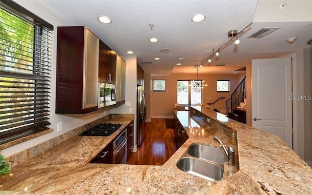 kitchen featuring light stone countertops, dark hardwood / wood-style floors, stainless steel appliances, a notable chandelier, and sink