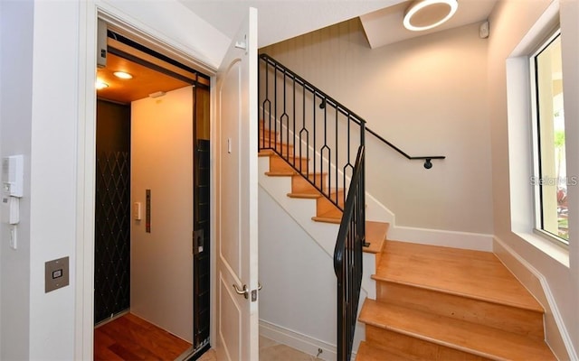 stairs with wood finished floors and elevator