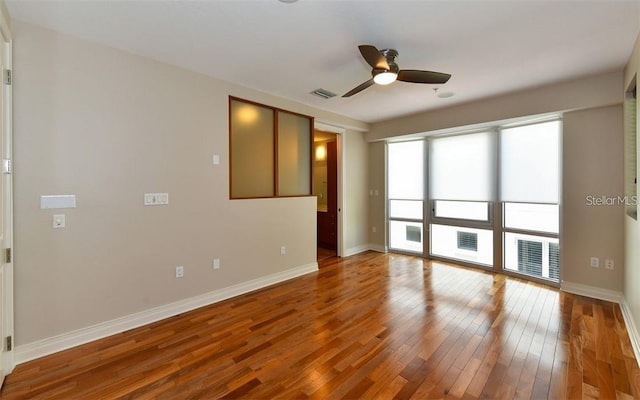 spare room with a ceiling fan, baseboards, visible vents, and hardwood / wood-style flooring