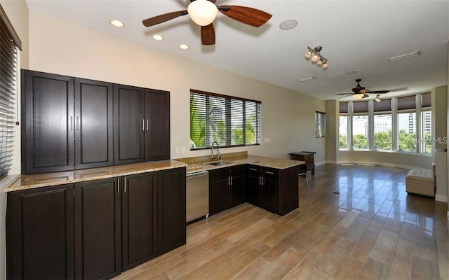 kitchen featuring a sink, light wood-style floors, a ceiling fan, open floor plan, and stainless steel dishwasher