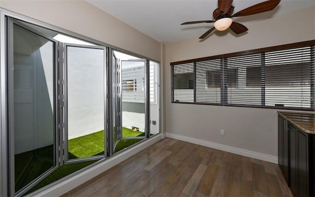 spare room featuring baseboards, ceiling fan, and dark wood-style floors