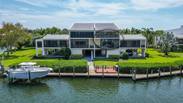 rear view of house with a yard, a sunroom, and a water view