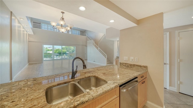 kitchen featuring light stone countertops, sink, dishwasher, decorative light fixtures, and light brown cabinets