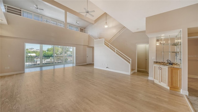 unfurnished living room with light hardwood / wood-style flooring, high vaulted ceiling, and ceiling fan