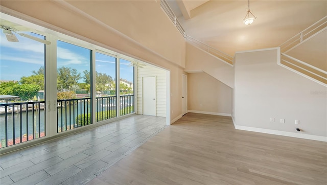 additional living space with a water view, ceiling fan, and hardwood / wood-style floors