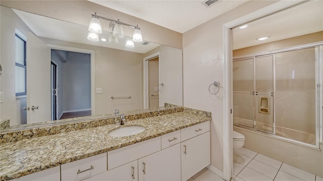 full bathroom featuring a textured ceiling, toilet, tile patterned floors, bath / shower combo with glass door, and vanity