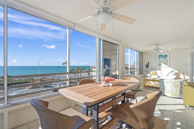 sunroom featuring ceiling fan and a water view