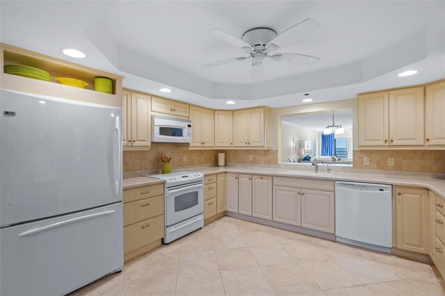 kitchen featuring a raised ceiling, light brown cabinets, and white appliances