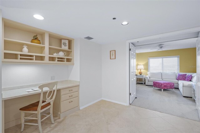 carpeted office space with ceiling fan and built in desk