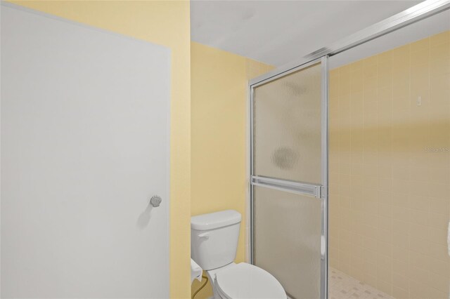 bathroom featuring toilet and a shower with shower door