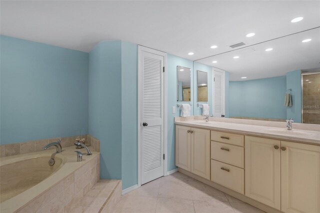 bathroom featuring tile patterned flooring, vanity, and a relaxing tiled tub