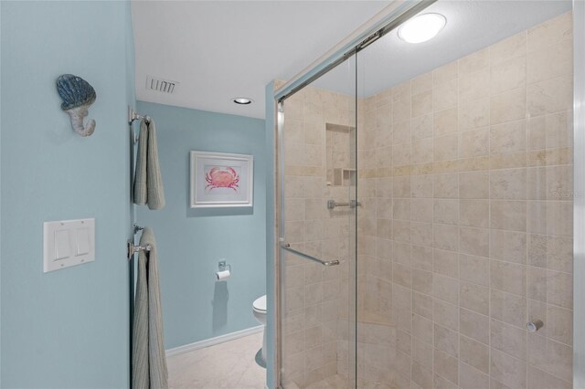 bathroom featuring tile patterned floors, a shower with shower door, and toilet