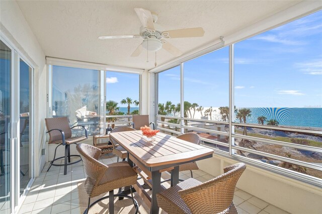 sunroom / solarium featuring ceiling fan and a water view