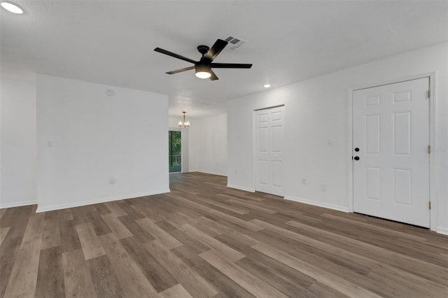 unfurnished living room featuring ceiling fan with notable chandelier and light hardwood / wood-style floors