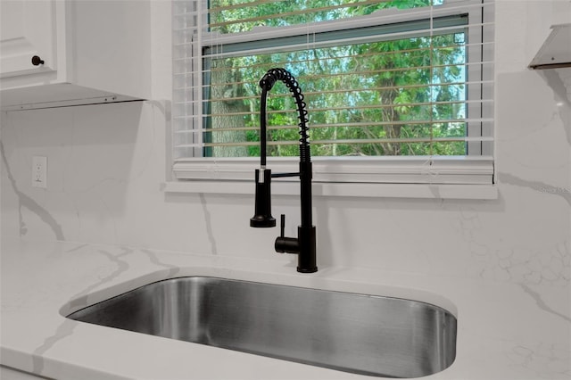 room details featuring white cabinetry, light stone countertops, and sink