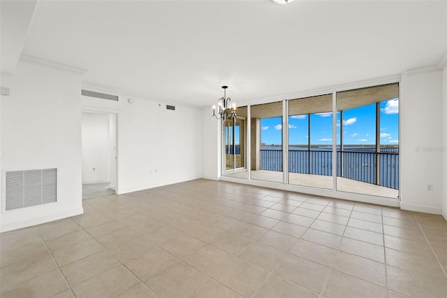 tiled empty room featuring crown molding, a water view, a notable chandelier, and floor to ceiling windows