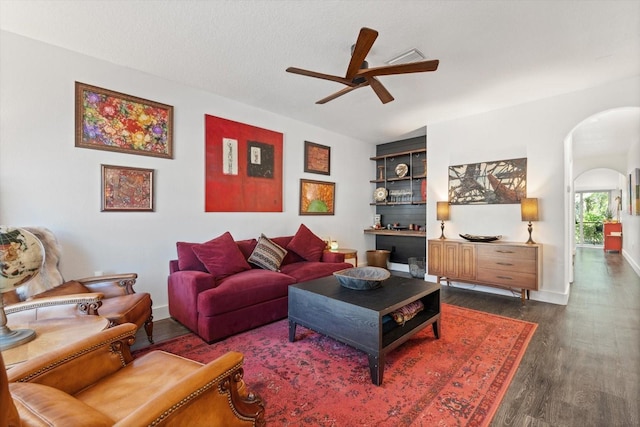 living room featuring dark wood-type flooring and ceiling fan