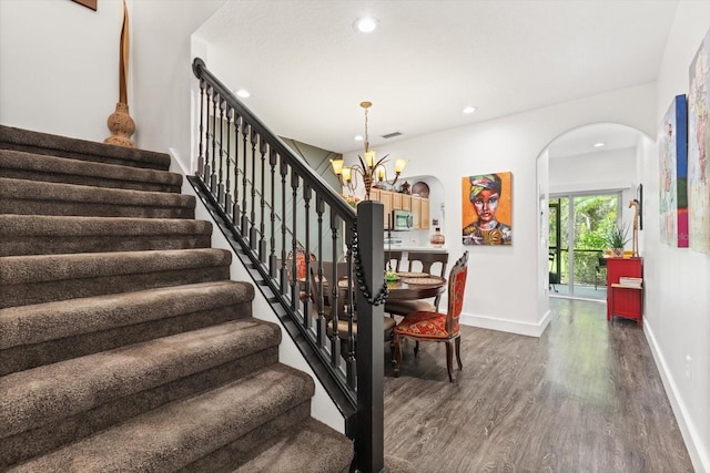 staircase with a chandelier and wood-type flooring