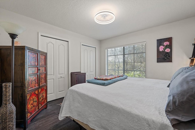 bedroom with dark hardwood / wood-style floors, multiple closets, and a textured ceiling