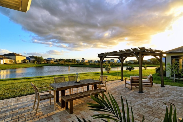 patio terrace at dusk featuring a yard, a water view, and a pergola