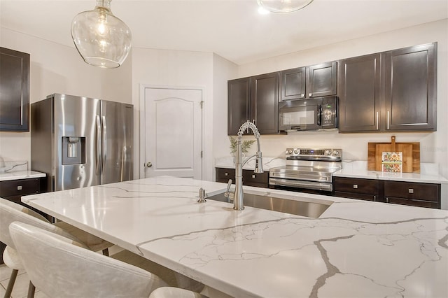 kitchen featuring dark brown cabinetry, appliances with stainless steel finishes, and decorative light fixtures