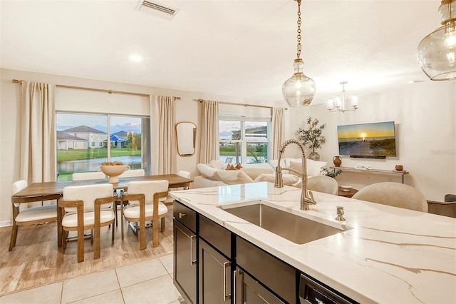 kitchen with light hardwood / wood-style flooring, hanging light fixtures, sink, light stone countertops, and a chandelier